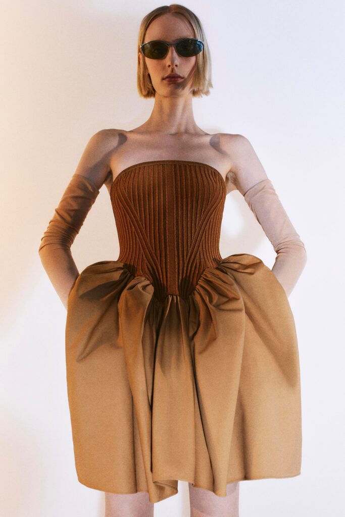 A fitted brown strapless dress with pleated and tiered design details.