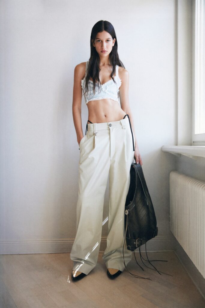 A relaxed white sleeveless top paired with high-waisted beige wide-leg pants.