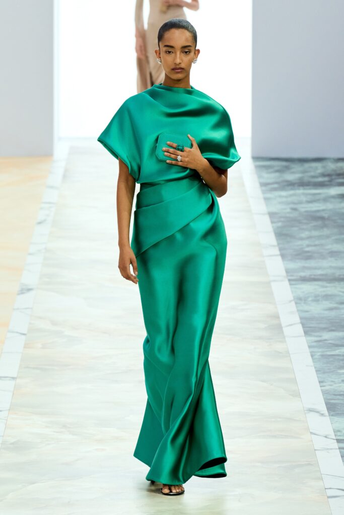 A fitted green silk dress with a high neckline and asymmetric design detail.