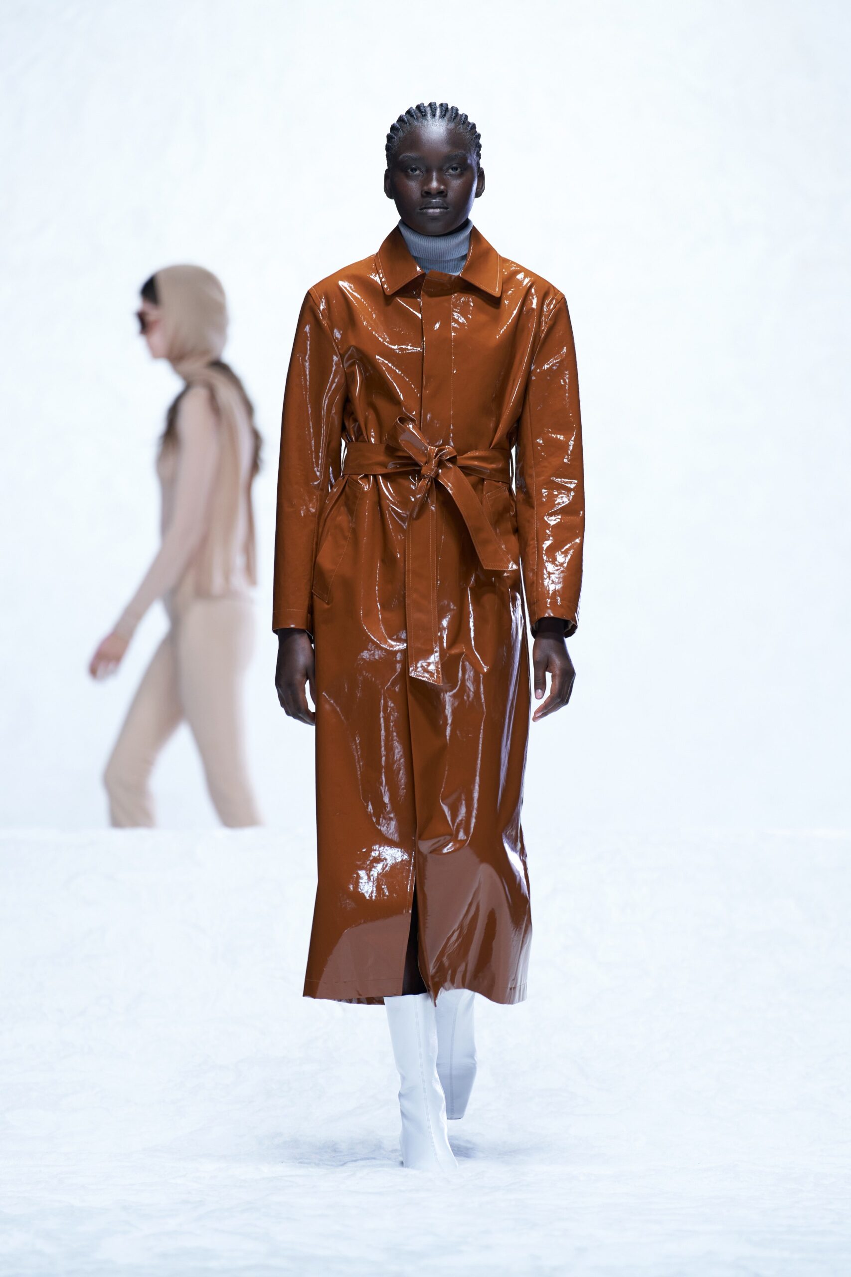 A fitted brown leather coat with long sleeves and a belted design.