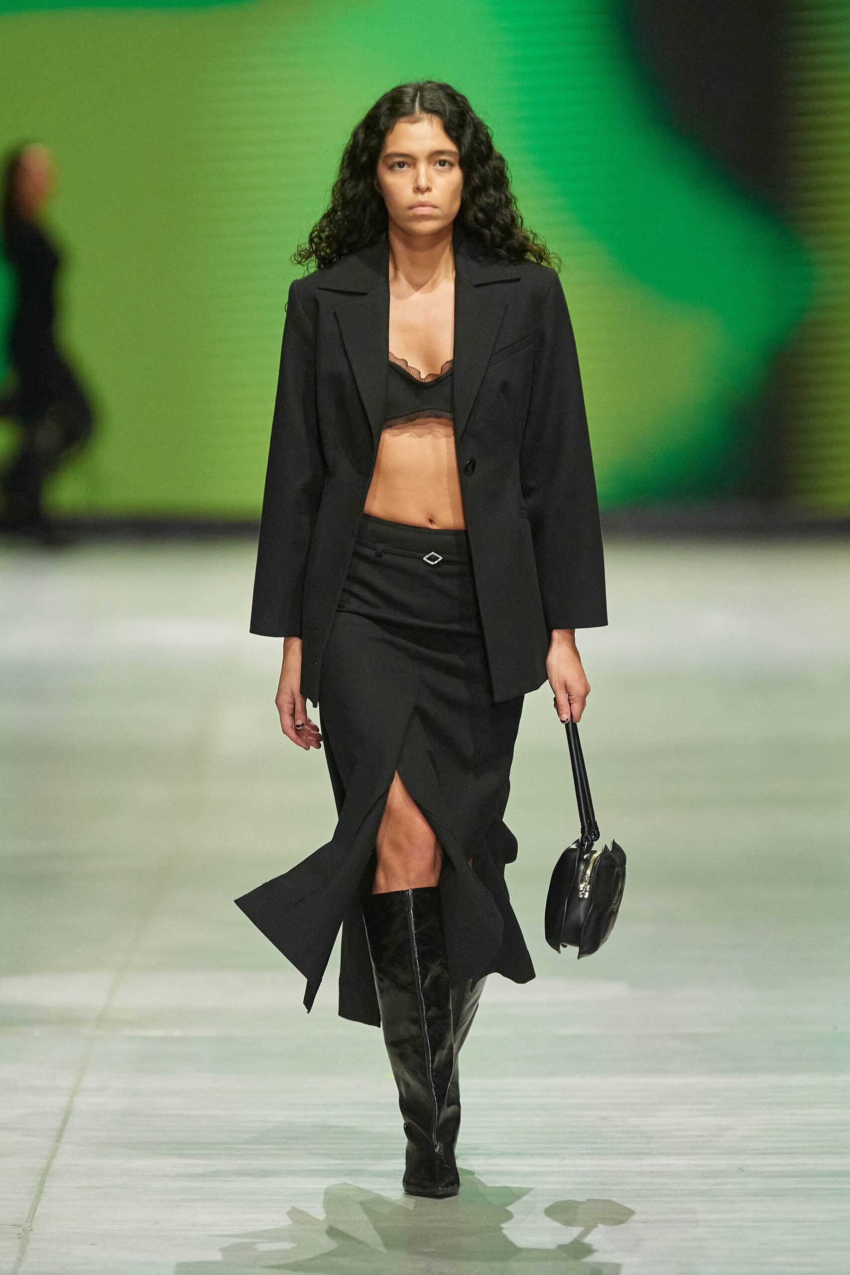 A fitted black blazer with a high-waisted asymmetric skirt featuring a slit.