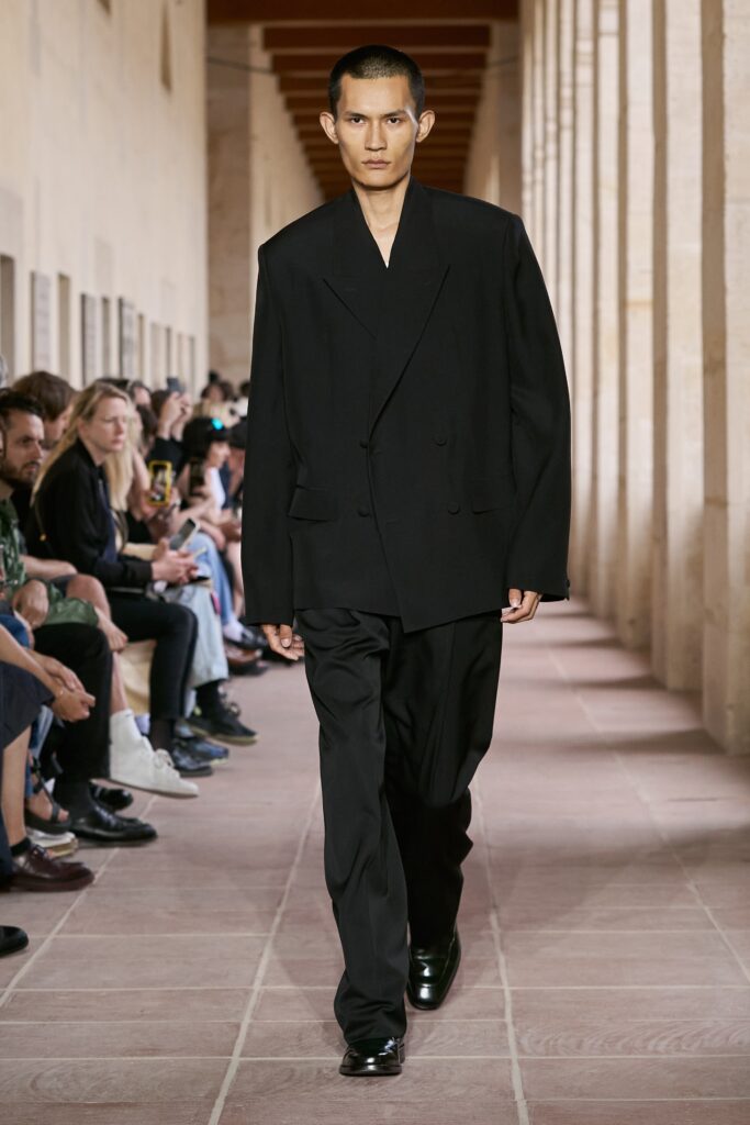 An oversized black wool suit with a double-breasted design and long sleeves.