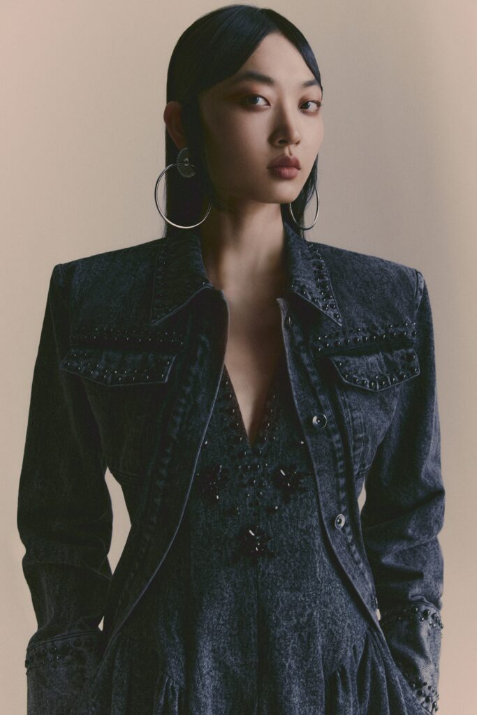 A fitted black denim dress with a V-neckline and embroidered details, paired with a matching jacket.