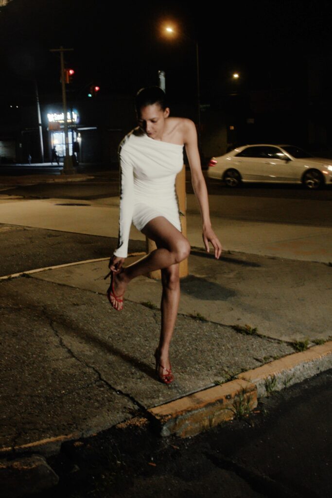 A fitted white sleeveless dress with an asymmetric design and mini length.