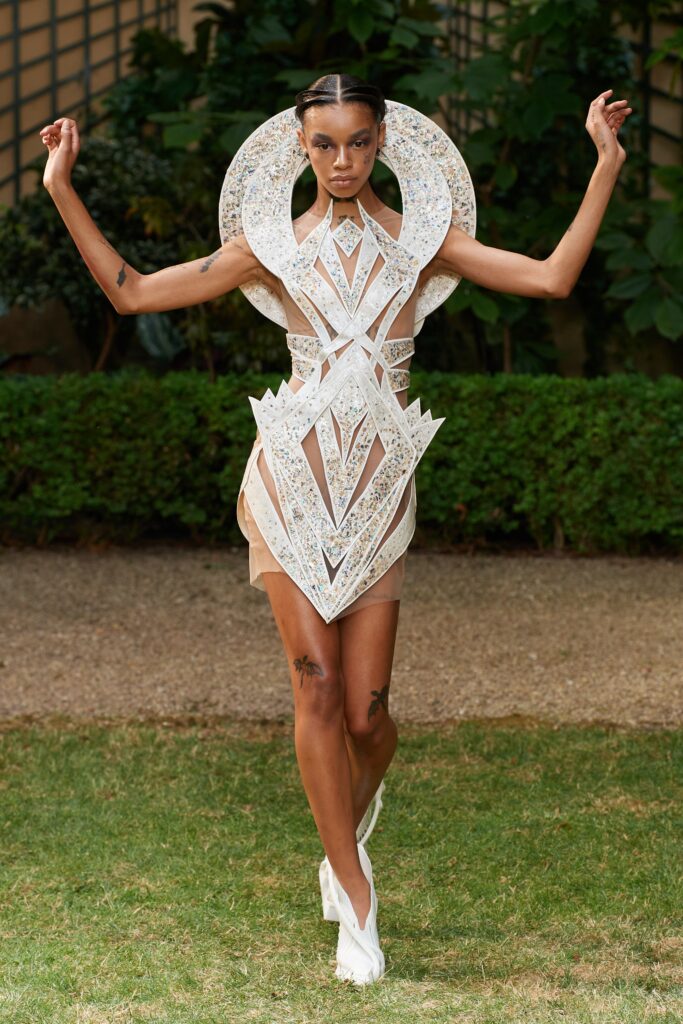 A fitted white lace dress with a high neckline and asymmetric design details.