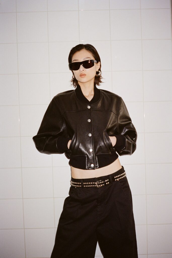 A fitted black leather jacket with a collared design paired with wide-leg black pants.