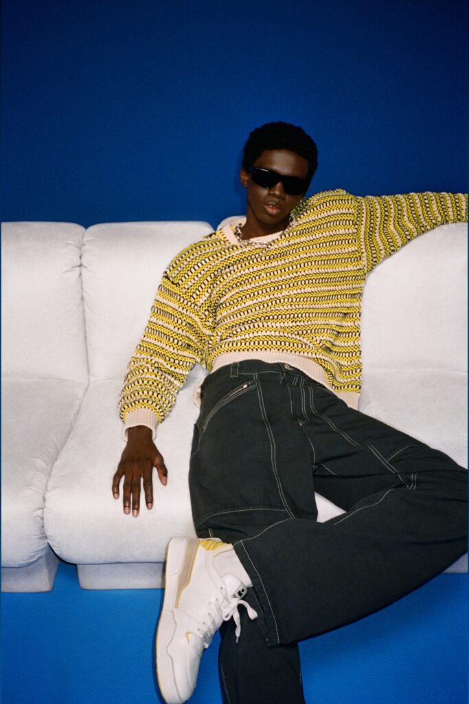 A relaxed-fit striped yellow and green sweater paired with black pants.