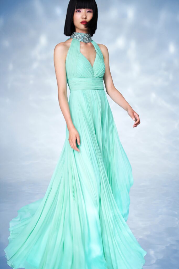 A fitted green silk gown with a halter neckline and pleated design.