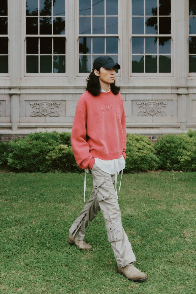 A relaxed red cotton long-sleeve sweater paired with beige layered pants.