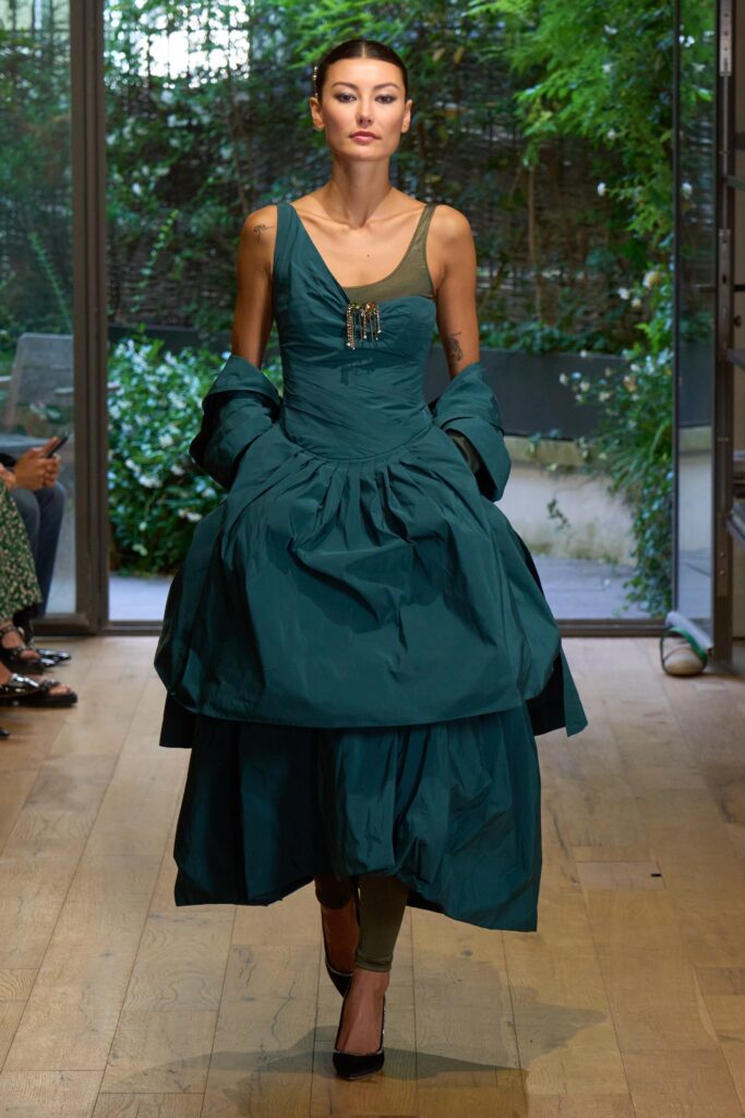 A fitted green silk sleeveless dress with a V-neckline and tiered silhouette.