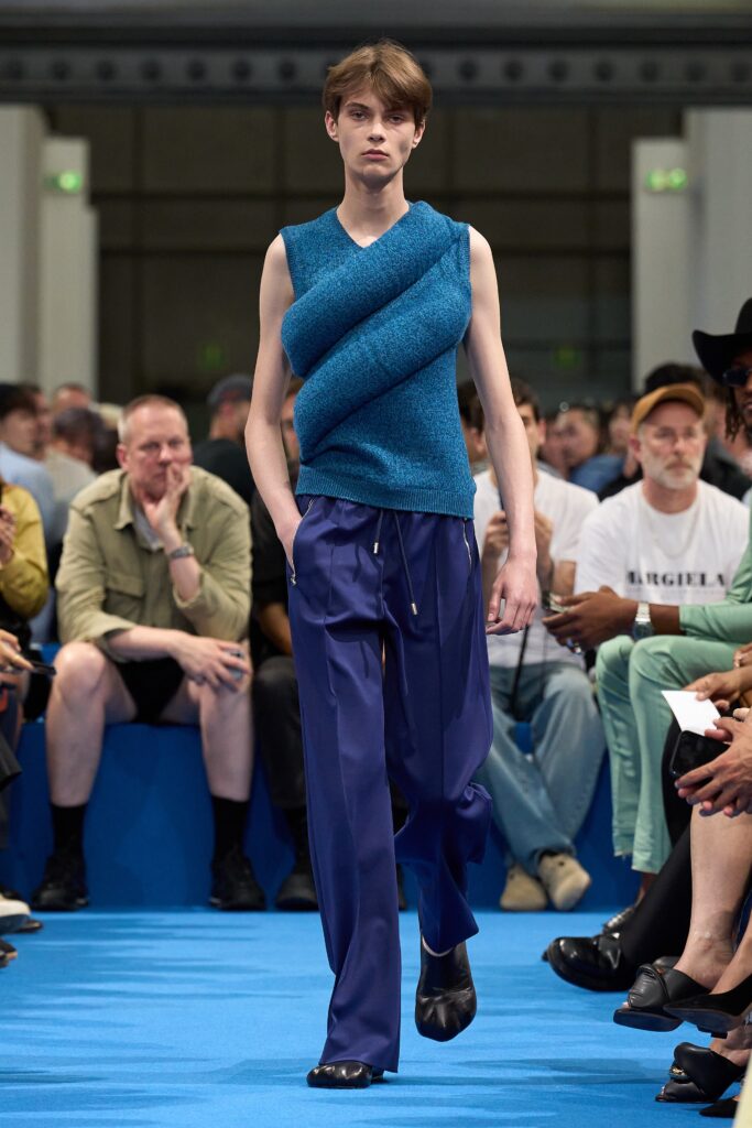 A relaxed fit blue asymmetric sleeveless top paired with black pants for a modern look.