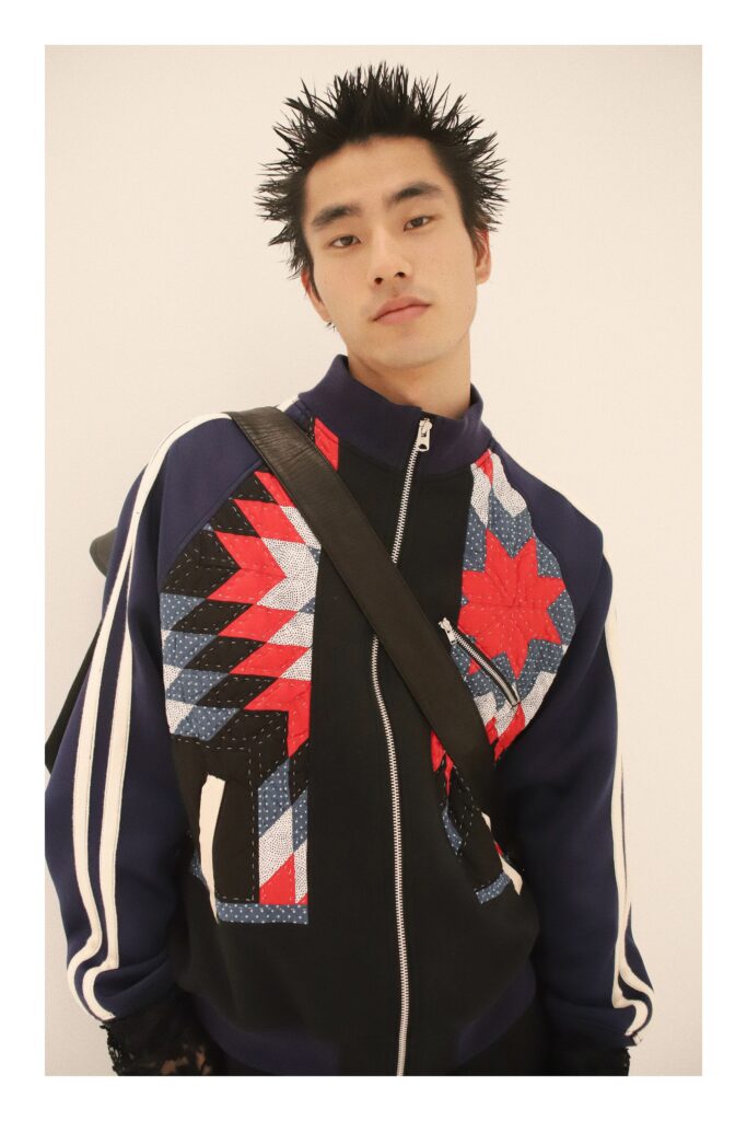 An oversized blue jacket with red and black patchwork design and a zippered front.