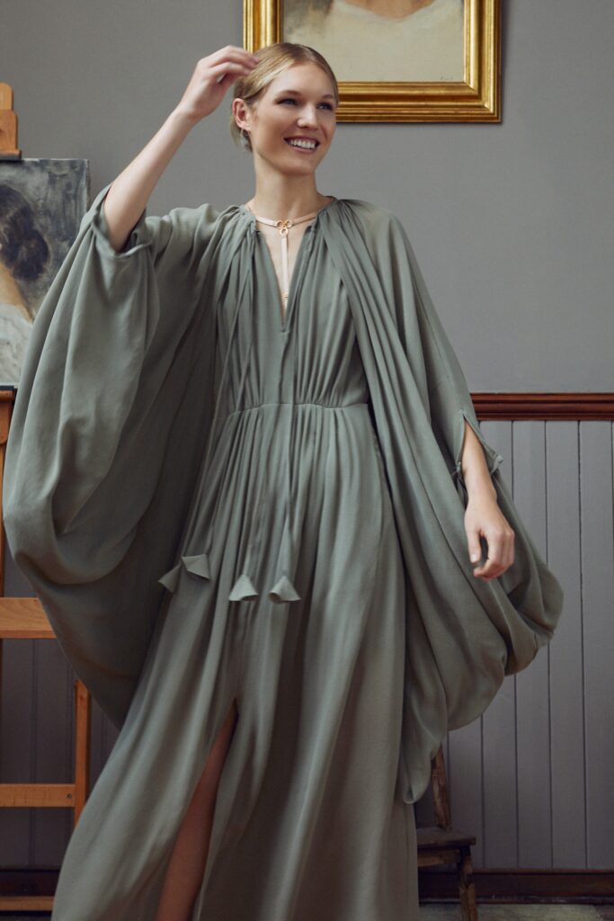 A relaxed green silk sleeveless dress with a V-neckline and draped, tiered design.