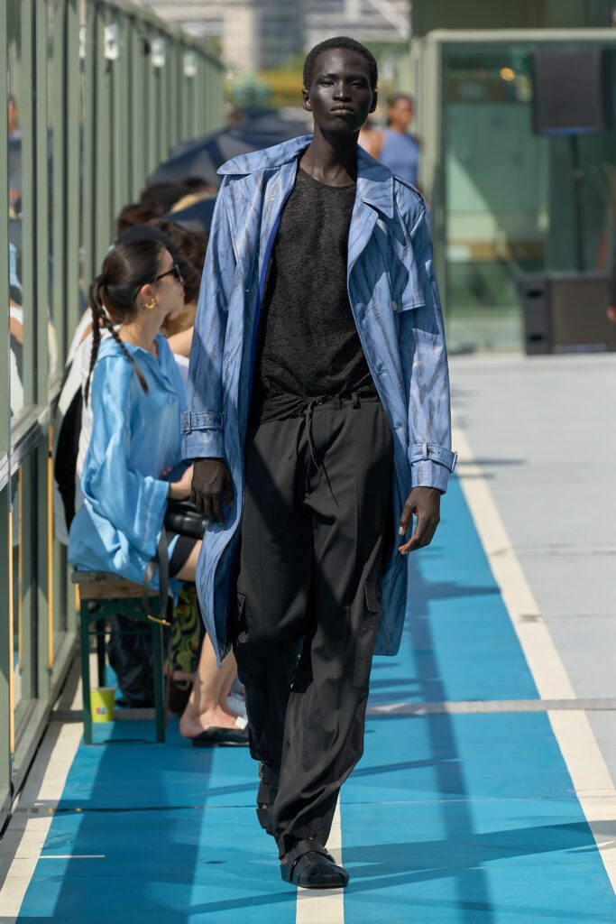 A relaxed blue cotton coat paired with black pants, featuring a long-sleeve and collared design.