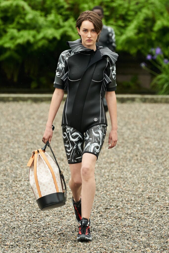 A fitted black neoprene jumpsuit with a high neckline and printed design details.