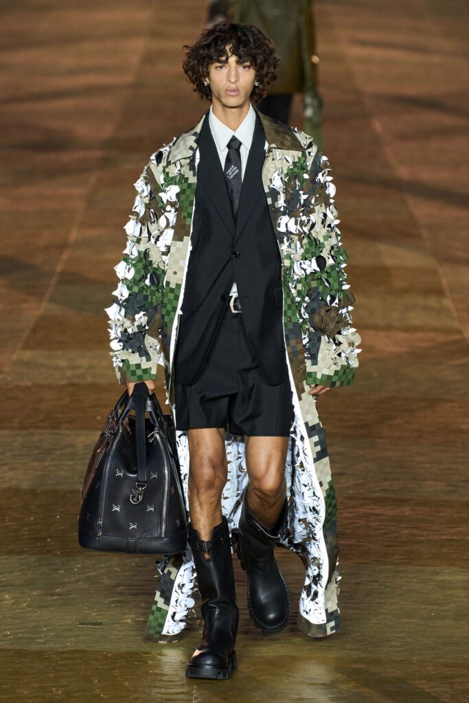 A relaxed fit multicolor coat layered over a black suit with a collared shirt.