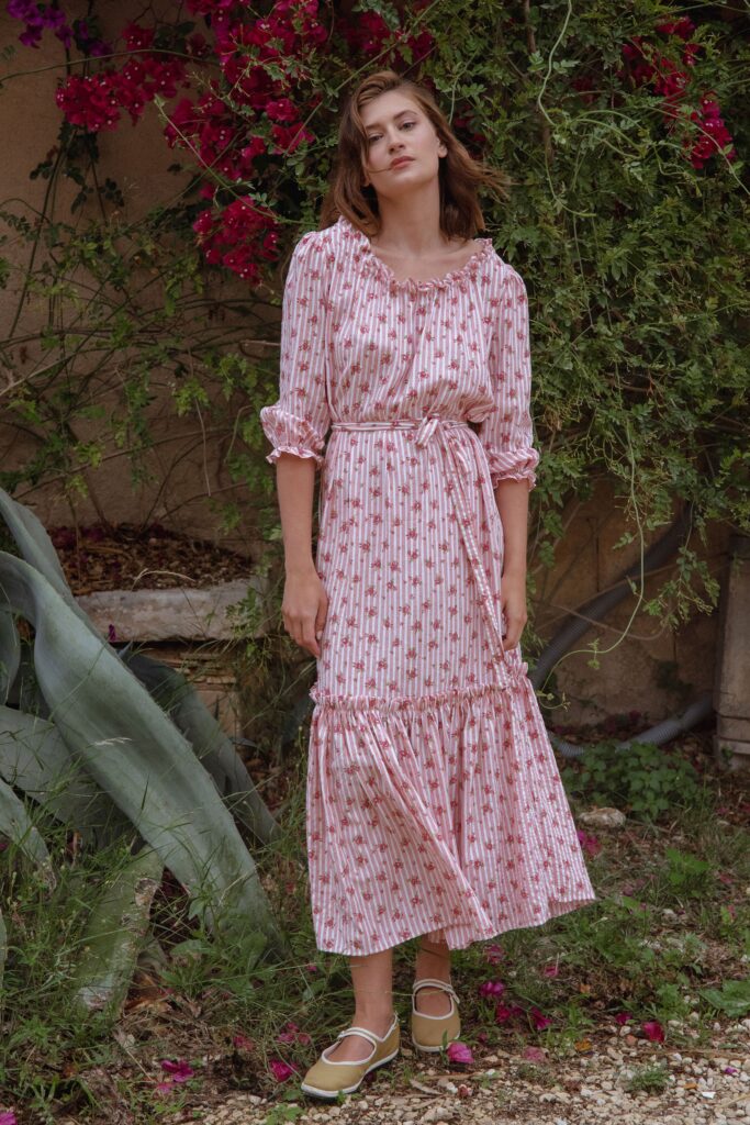 A relaxed pink cotton long-sleeve dress with a V-neckline and tiered design.