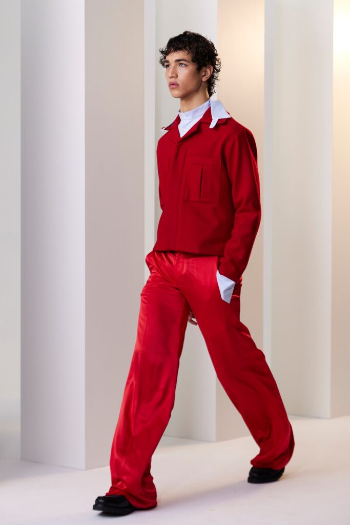 A relaxed red silk shirt with long sleeves and a collared neckline paired with straight-leg pants.