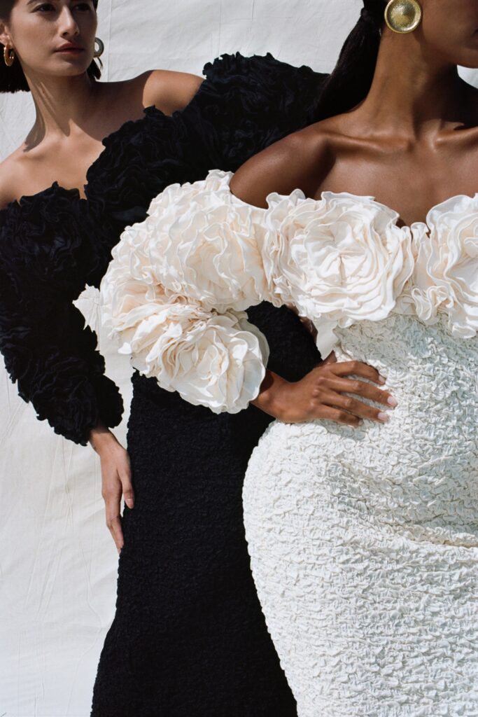 A fitted black and white dress with off-shoulder design and ruffled details.