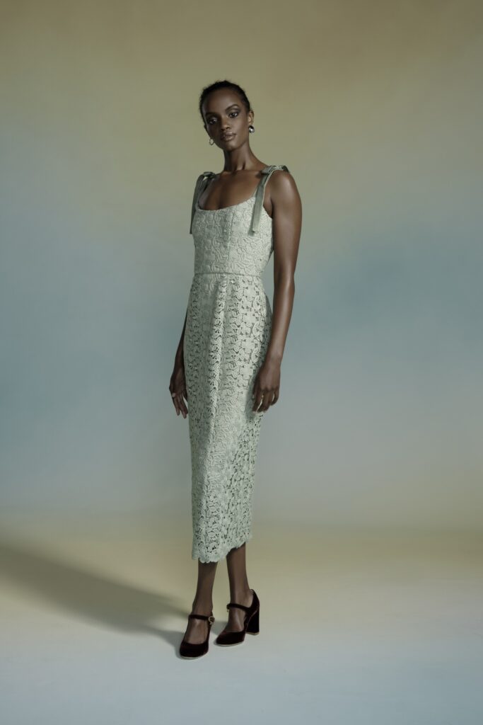 A fitted green lace dress with a high neckline and tiered design details.