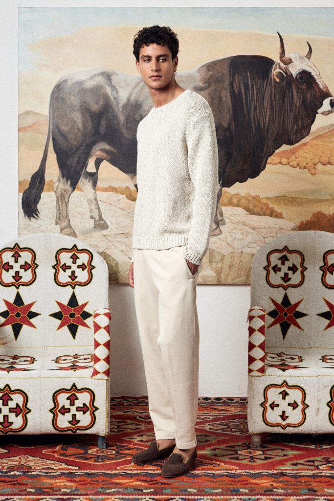 A relaxed white cotton long-sleeve sweater paired with beige trousers.