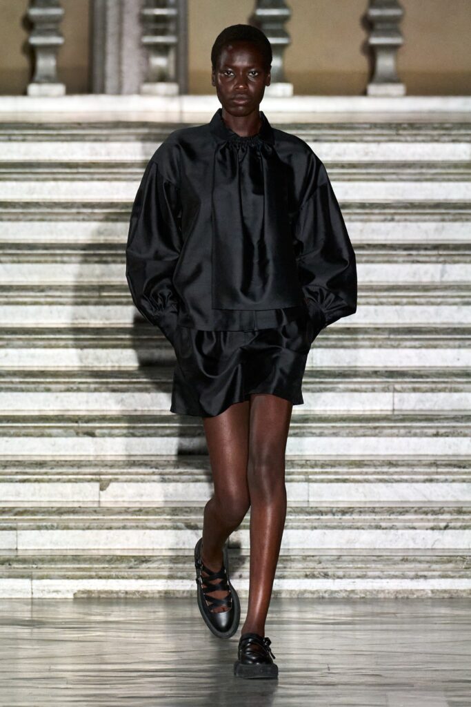 A relaxed black silk top with long sleeves and an asymmetric skirt.