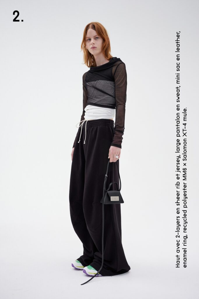A relaxed black long-sleeve hooded sweater layered over white pants for a contemporary look.