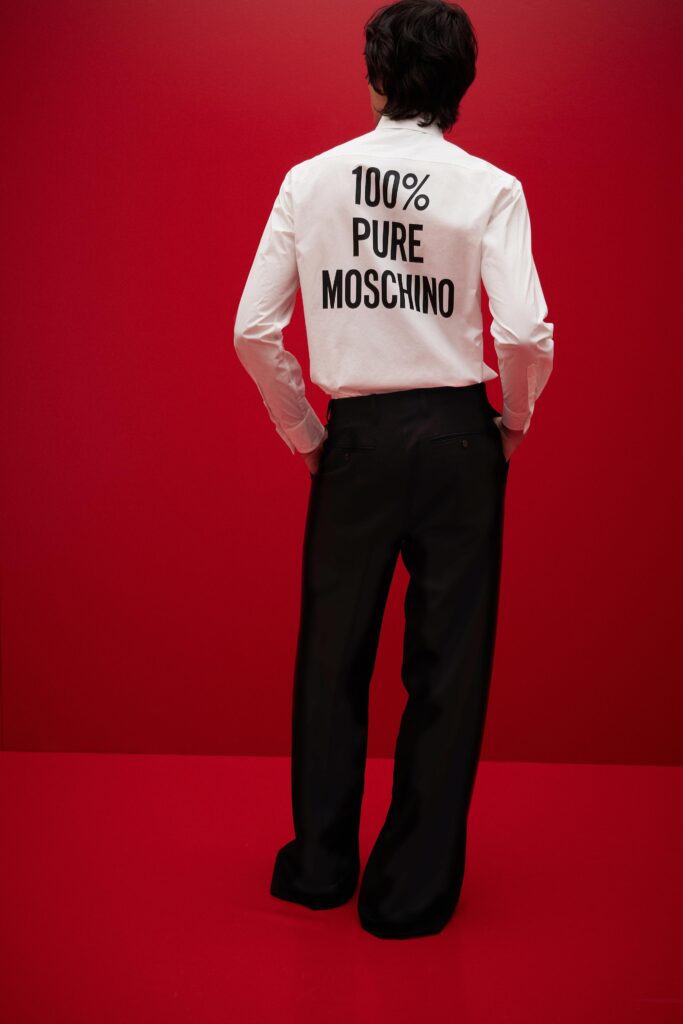 A relaxed fit white long-sleeve shirt with a printed design paired with black pants.