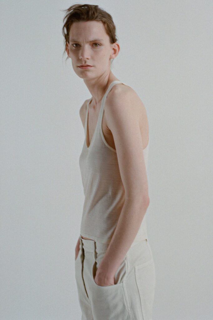 A fitted beige cotton tank-top with a V-neckline paired with straight-leg pants.