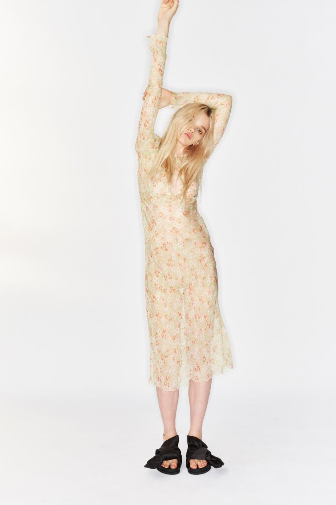 A fitted beige silk dress with long sleeves and a V-neckline featuring a floral pattern.