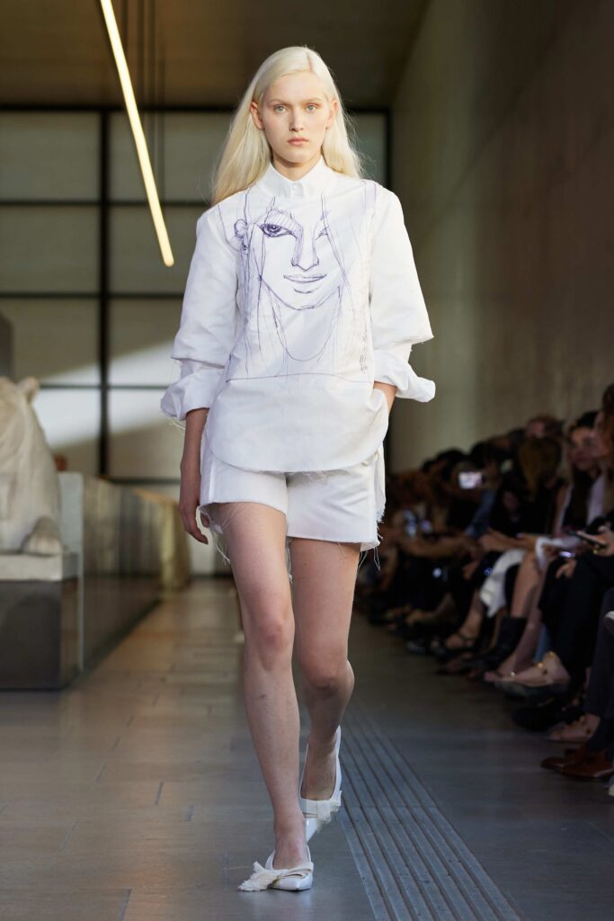 An oversized white cotton shirt paired with matching shorts, featuring a unique artistic design.