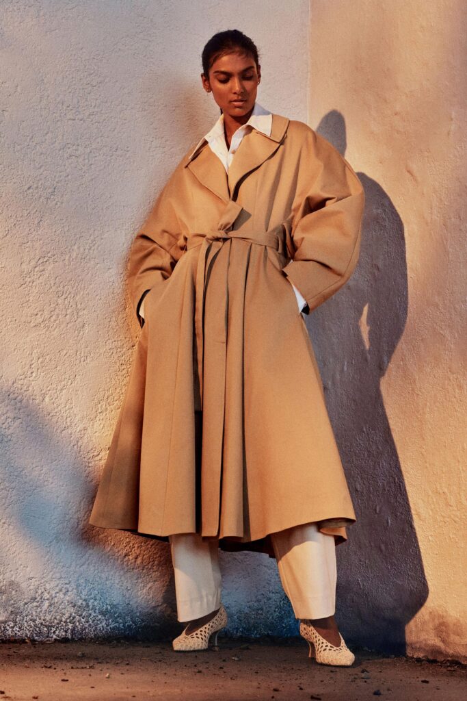 A relaxed beige cotton coat with long sleeves and a belted design.