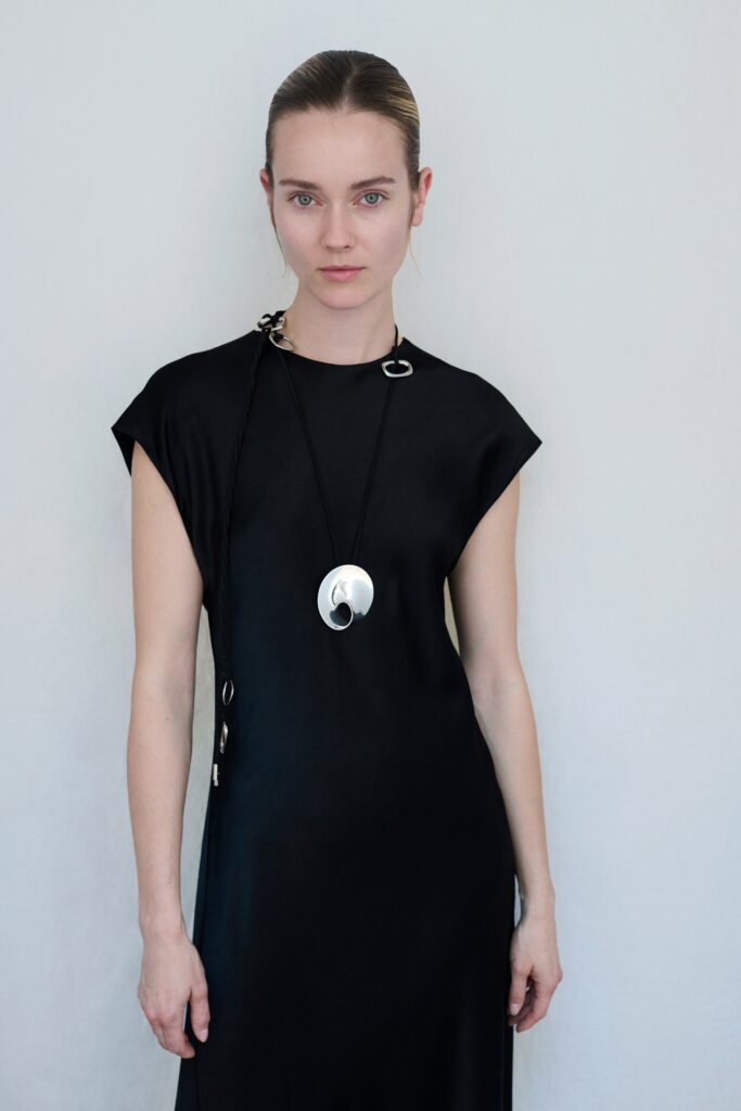A relaxed black silk sleeveless dress with a high-neck design and straight silhouette.