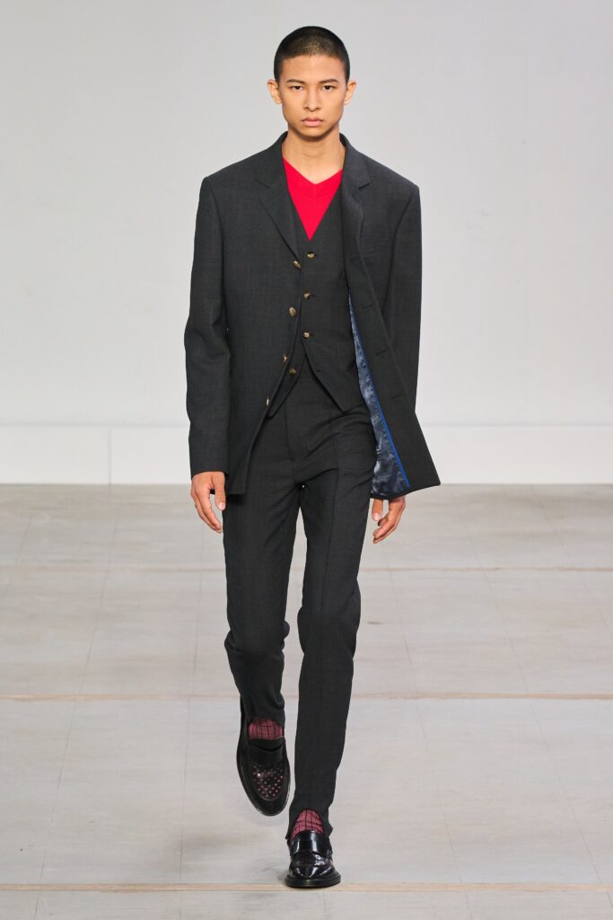 A tailored black wool suit with long sleeves and a collared shirt underneath.