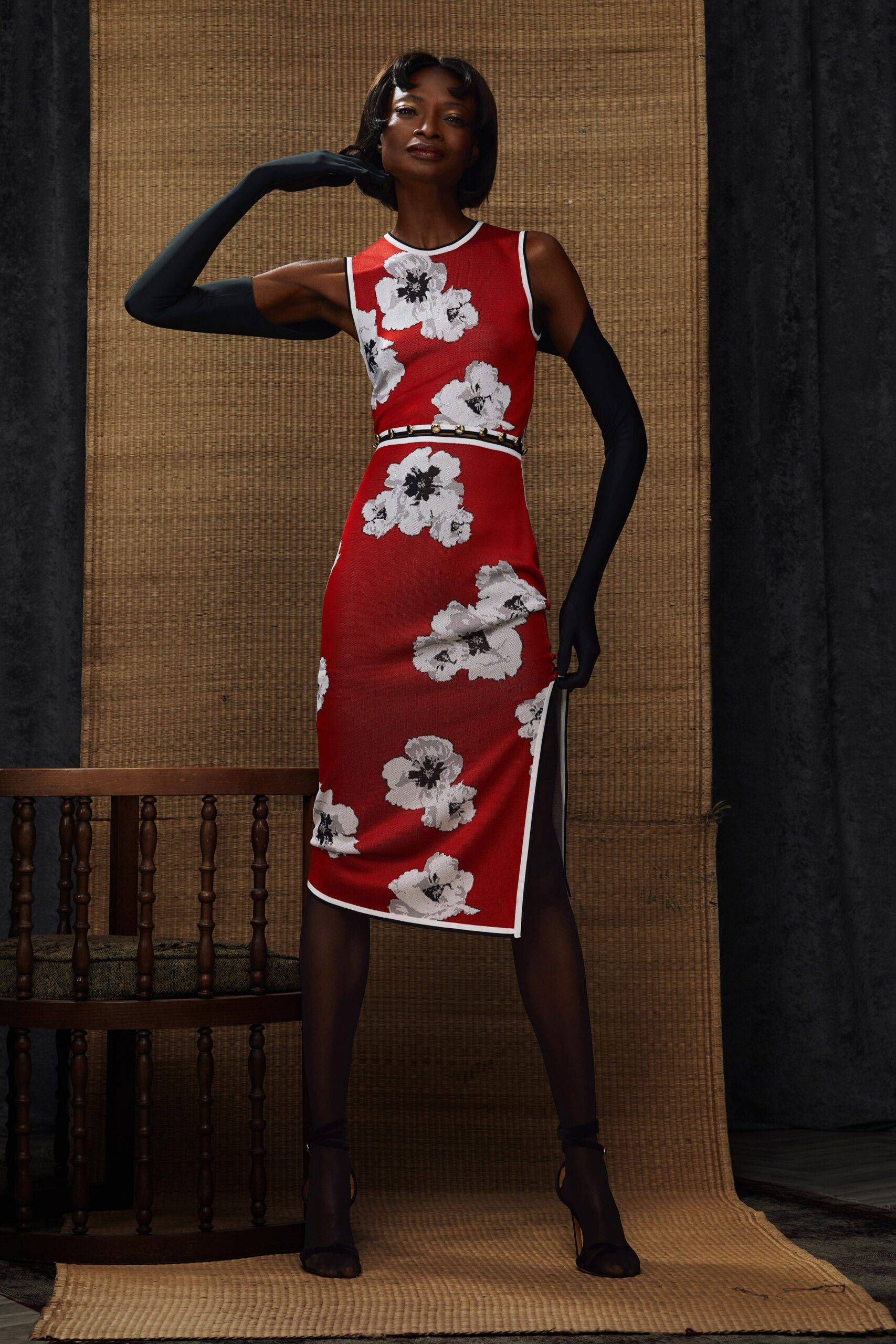 A fitted red dress with a floral pattern, sleeveless design, and high-neck construction.