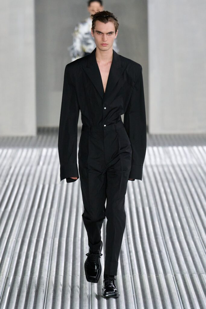 A fitted black cotton suit with a collared long-sleeve design and structured silhouette.