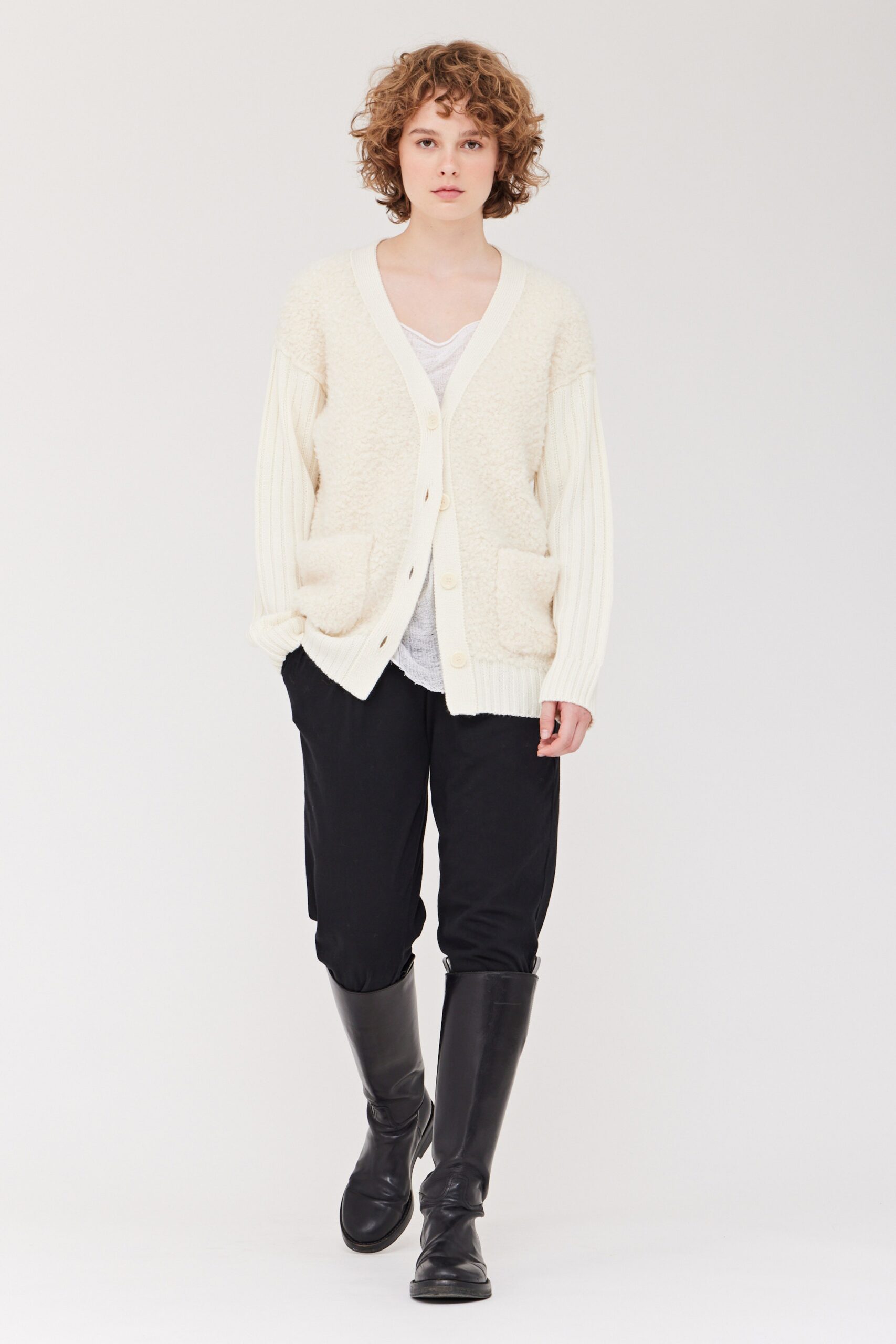 A relaxed white cardigan with long sleeves paired with black pants, featuring a buttoned design.