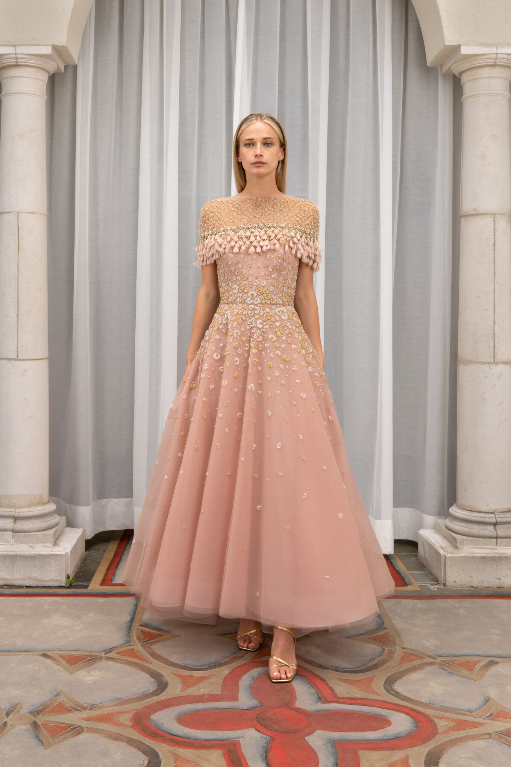 A fitted pink embroidered tulle gown with a high neckline and tiered design details.