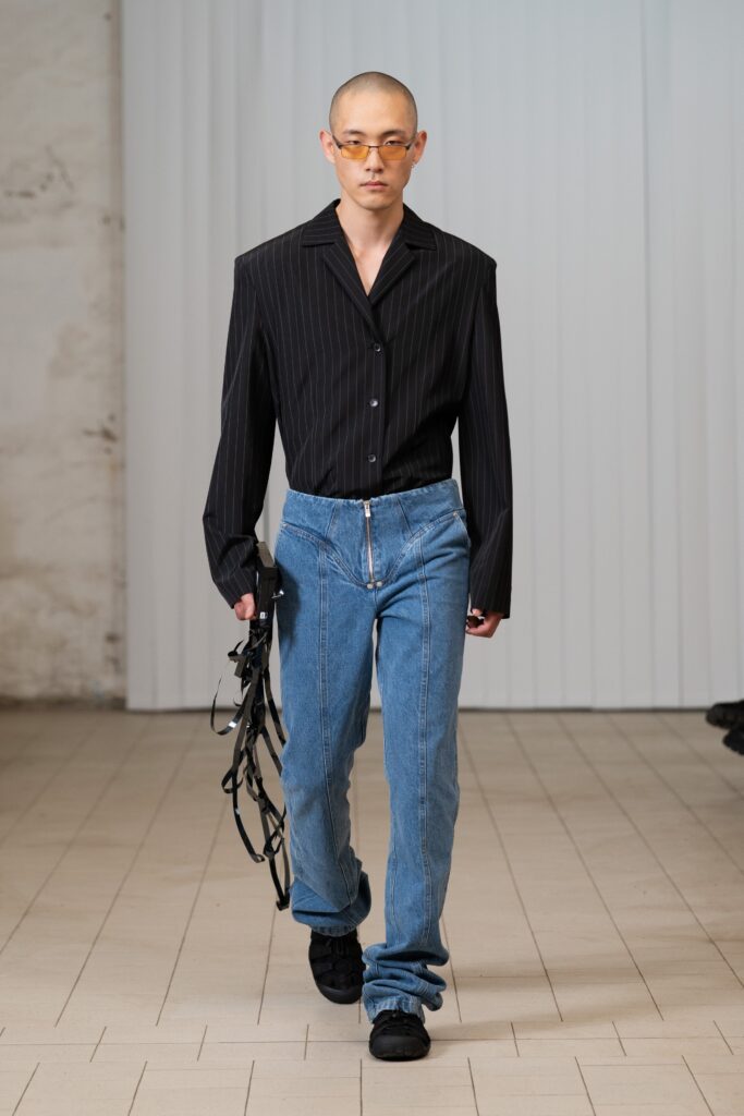 A fitted black buttoned shirt paired with high-waisted blue denim pants for a stylish look.