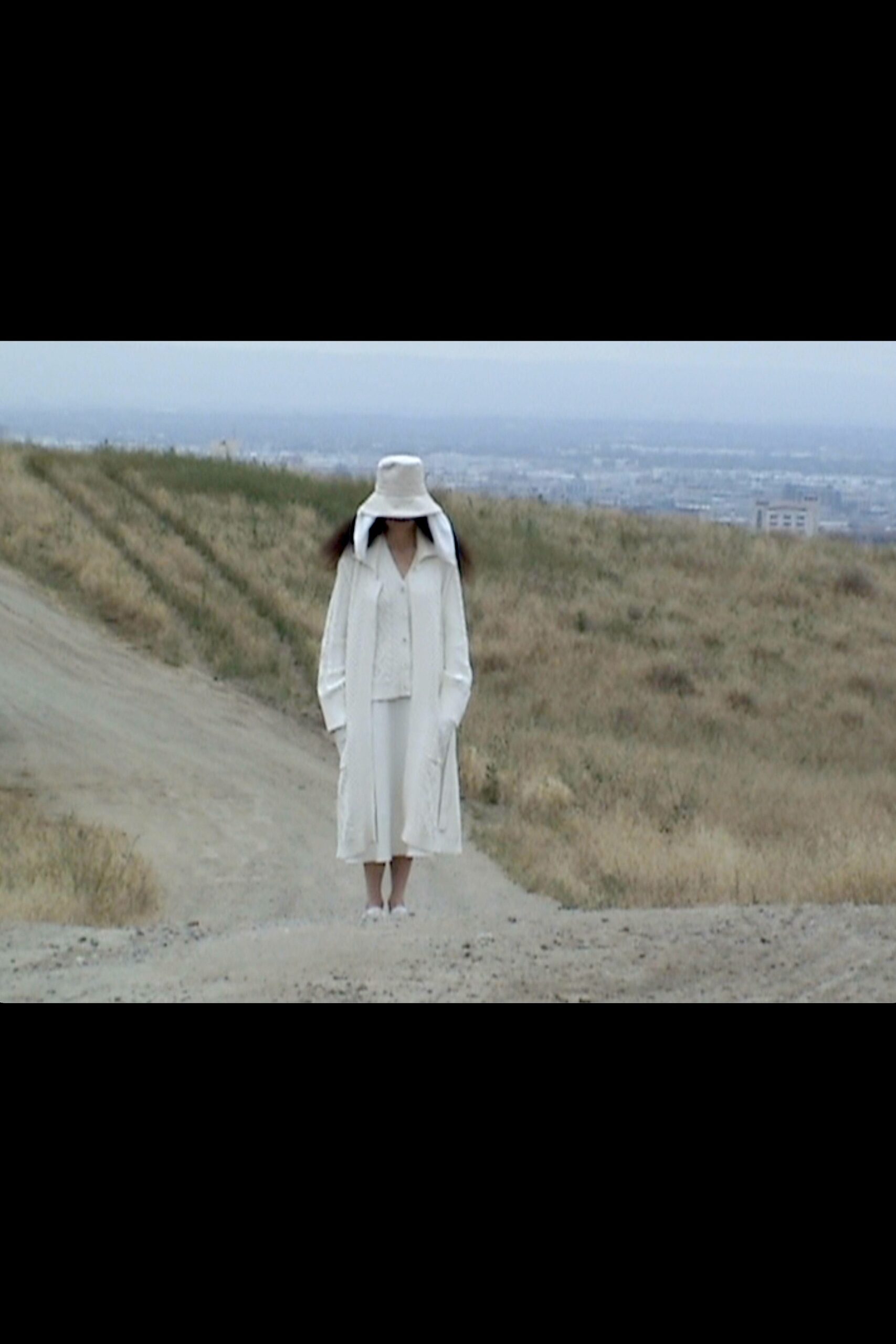 A relaxed white dress with a long-sleeve collared coat layered over it.