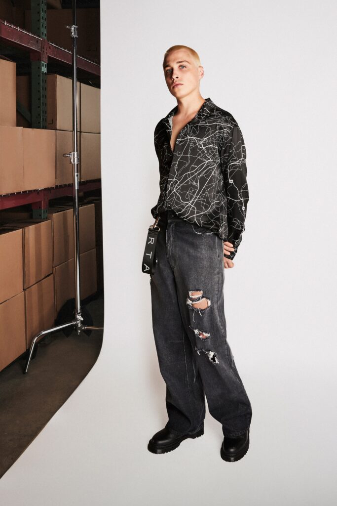 A relaxed black printed long-sleeve shirt paired with high-waisted distressed gray pants.