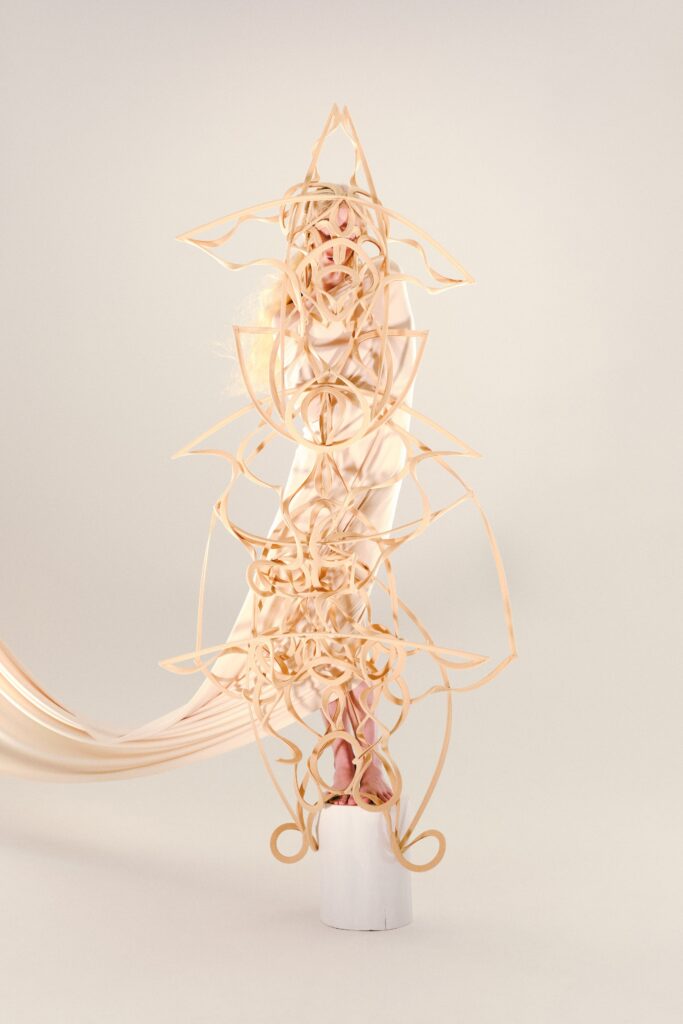 An asymmetric layered beige silk dress featuring intricate design elements and flowing details.