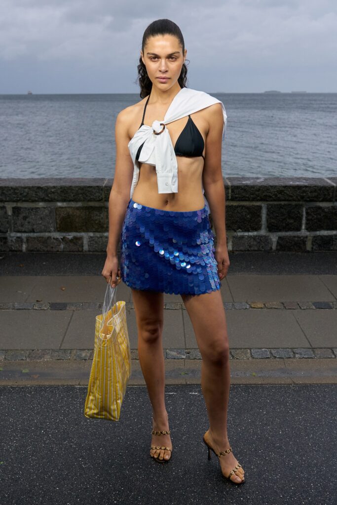 A fitted black sleeveless top with a collared detail paired with a mini blue sequin skirt.