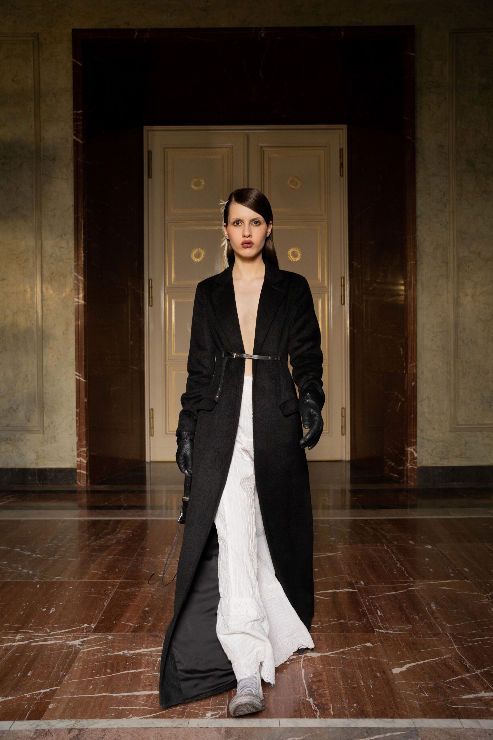 A fitted black wool coat paired with white pants, featuring a layered design.