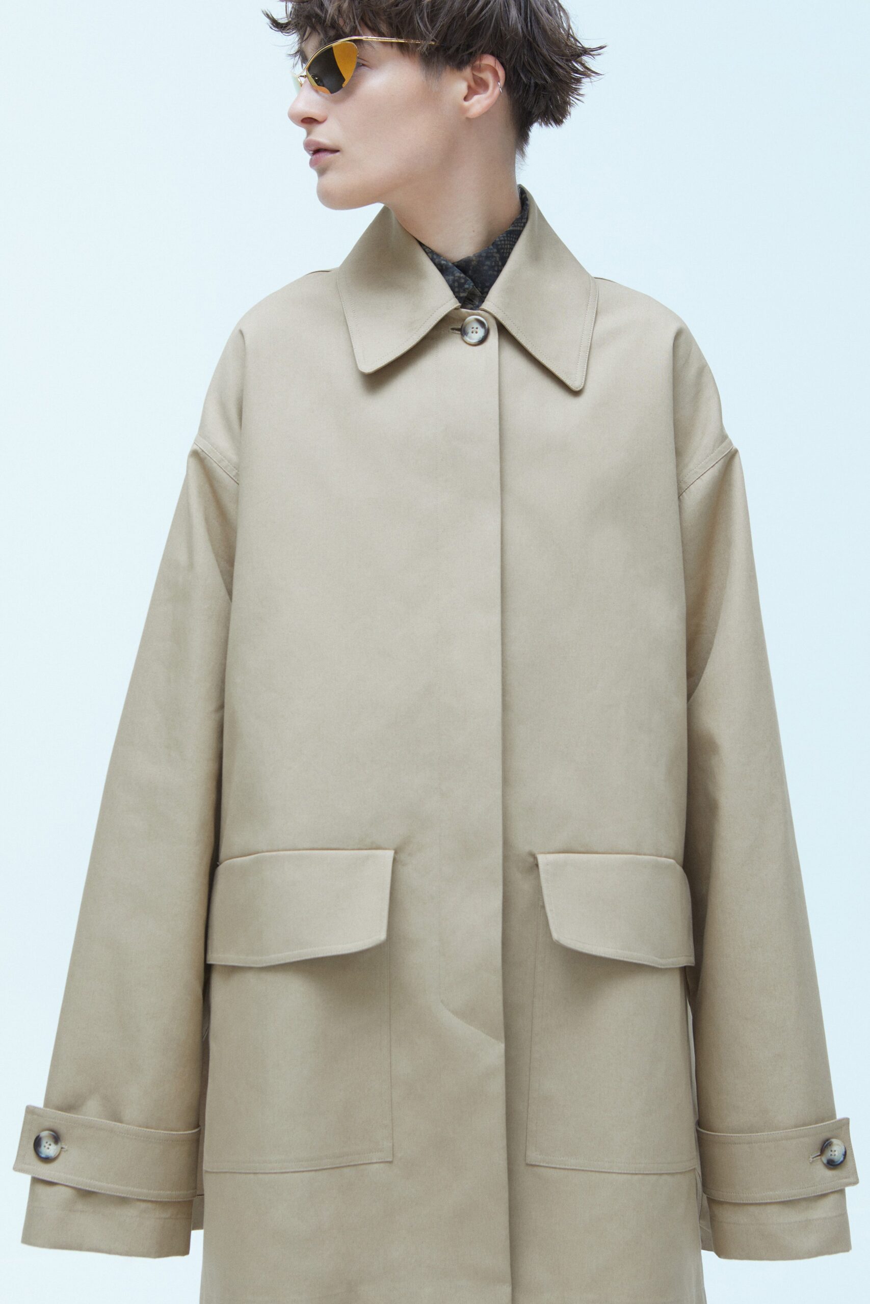 An oversized beige coat with long sleeves and a collared design, featuring button details.