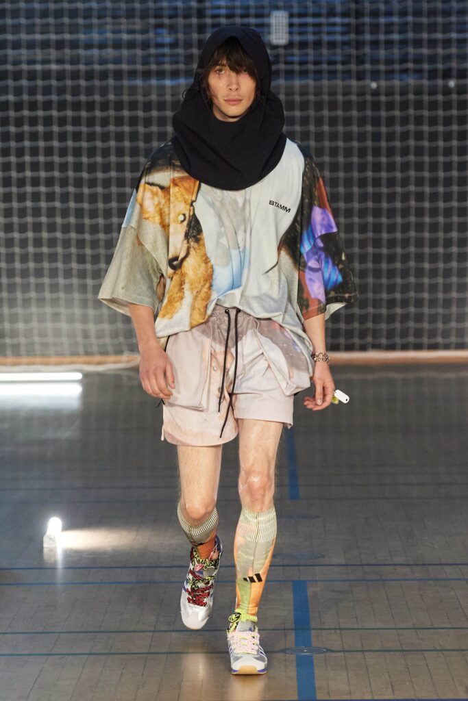 A relaxed multicolor cotton shirt with short sleeves and printed design, paired with pink shorts.