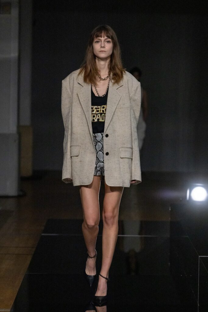 An oversized beige blazer paired with printed black shorts for a chic runway look.