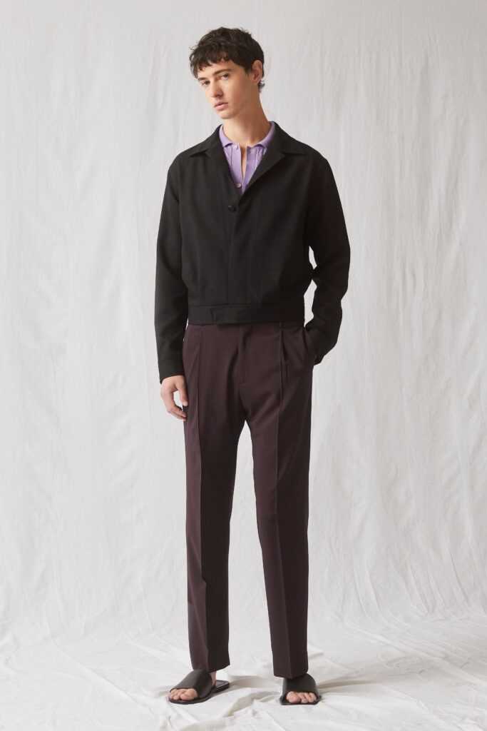 A tailored black jacket with long sleeves paired with straight-leg burgundy pants.