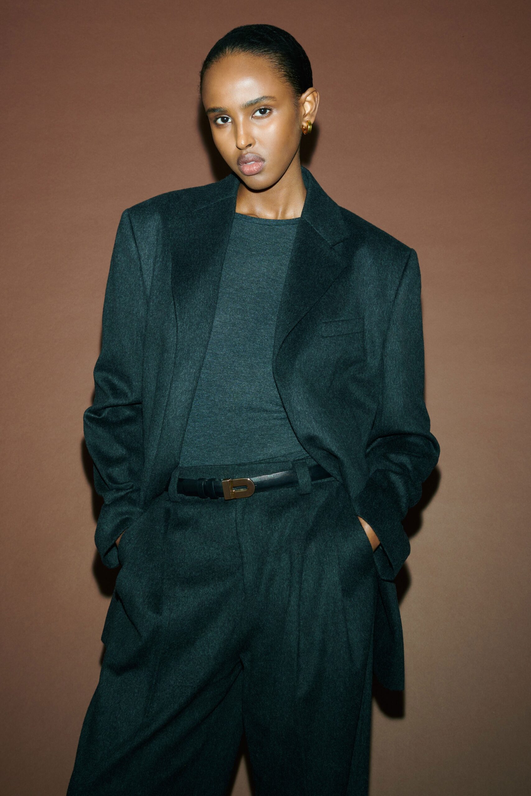 A relaxed black wool blazer paired with straight-leg pants, featuring a long-sleeve and collared design.