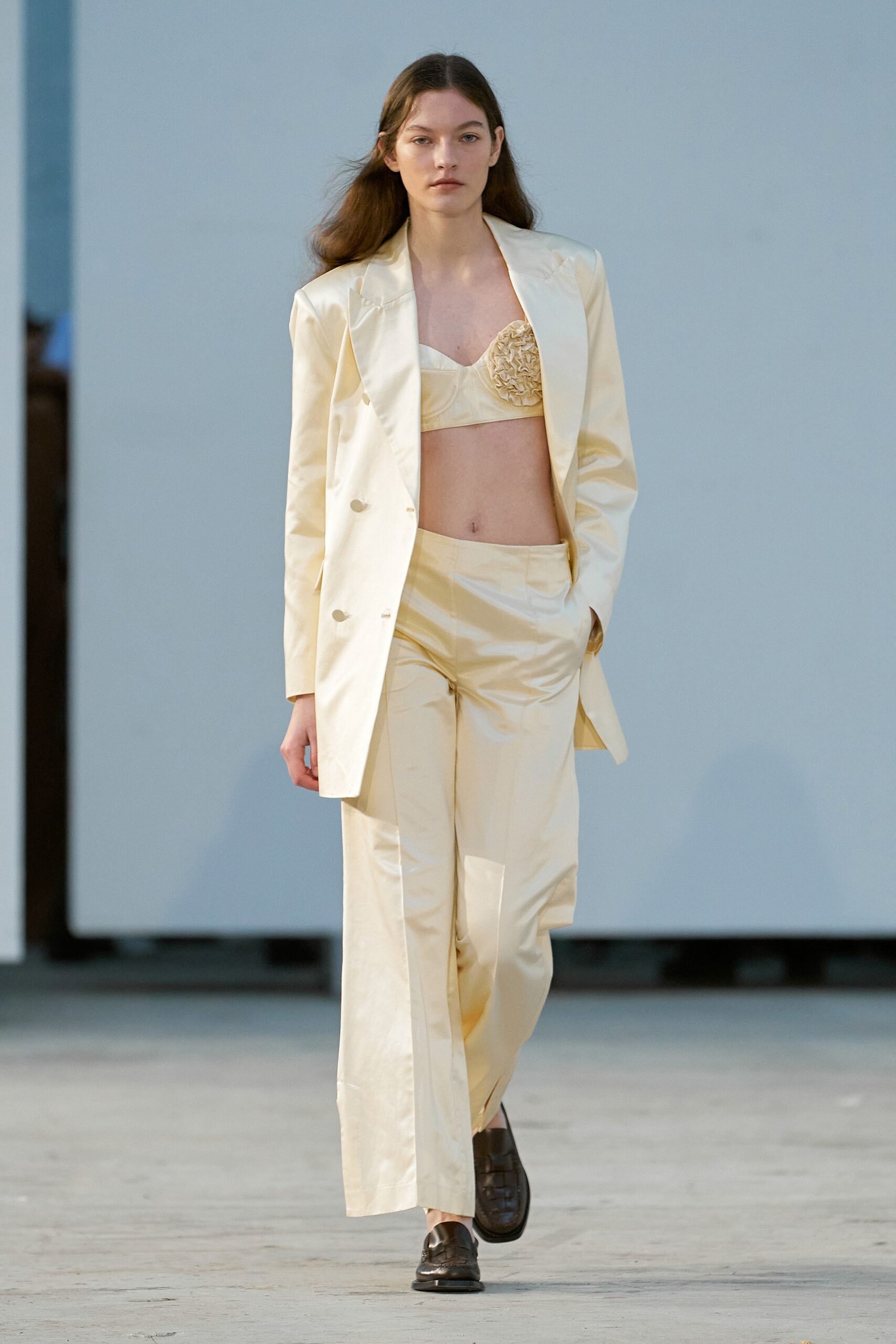 A tailored cream silk blazer paired with straight-leg pants, featuring a buttoned design.
